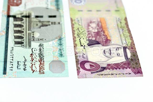 The obverse sides of Saudi Arabia 5 five riyals banknote with 5 LE five Egyptian pounds bill isolated on a white background, Selective focus of Egypti The obverse sides of Saudi Arabia 5 five riyals banknote with 5 LE five Egyptian pounds bill isolated on a white background, Selective focus of Egypti