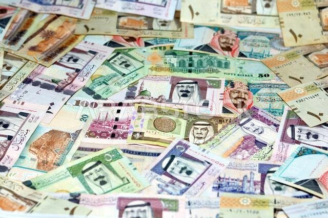 Background of a pile of Saudi Arabia riyals banknotes money bills of different values from different times, selective focus of a stack of Saudi riyals