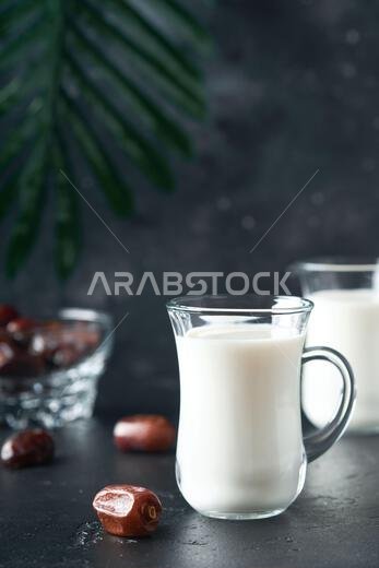 مأكولات ومشروبات رمضان كريم. طبق من التمر، وكوب من الحليب، وسعفة نخلة على خلفية سوداء. نمط حياة مسلم صالح. طعام نباتي. S