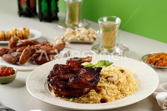 Kabsa, Arabian Dish made of Long Grain Basmati Rice, Roasted Whole Chicken, Onion, Spices (Cardamom, Saffron, Cinnamon, Bay leaves), Topping with Rais