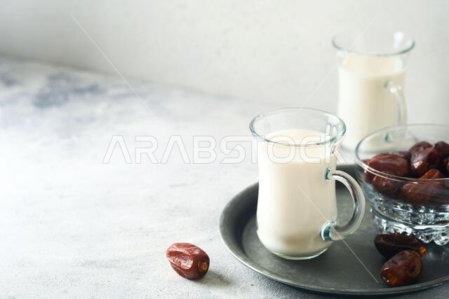 Ramadan Kareem food and drinks. Plate of dates, glass of milk and date palm branch on light grey background. Righteous Muslim Lifestyle. Place for tex