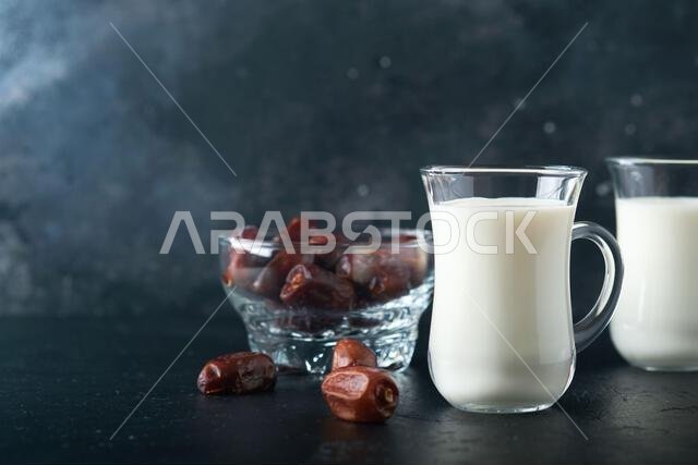 مأكولات ومشروبات رمضان كريم. طبق من التمر، وكوب من الحليب، وسعفة نخلة على خلفية سوداء. نمط حياة مسلم صالح. طعام نباتي. S