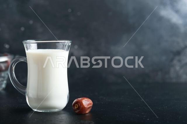 مأكولات ومشروبات رمضان كريم. طبق من التمر، وكوب من الحليب، وسعفة نخلة على خلفية سوداء. نمط حياة مسلم صالح. طعام نباتي. S