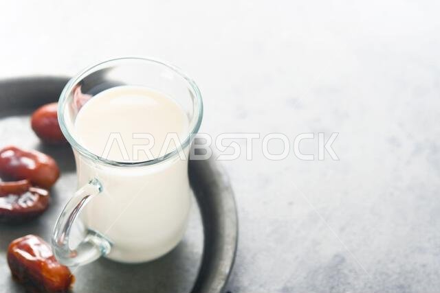 مأكولات ومشروبات رمضان كريم. طبق من التمر، وكوب من الحليب، وسعفة نخلة على خلفية رمادية فاتحة. نمط حياة مسلم صالح. مساحة للنصوص مأكولات ومشروبات رمضان كريم. طبق من التمر، وكوب من الحليب، وسعفة نخلة على خلفية رمادية فاتحة. نمط حياة مسلم صالح. مساحة للنصوص