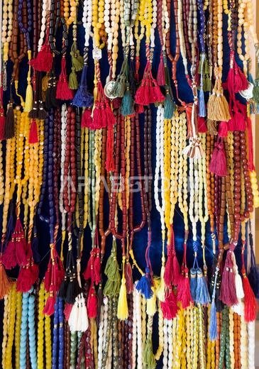 Large collection of beautifully colored prayer beads hanging in rows on display shelf. Large collection of beautifully colored prayer beads hanging in rows on display shelf.