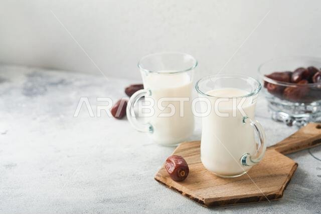 مأكولات ومشروبات رمضان كريم. طبق من التمر، وكوب من الحليب، وسعفة نخلة على خلفية رمادية فاتحة. نمط حياة مسلم صالح. مساحة للنصوص مأكولات ومشروبات رمضان كريم. طبق من التمر، وكوب من الحليب، وسعفة نخلة على خلفية رمادية فاتحة. نمط حياة مسلم صالح. مساحة للنصوص