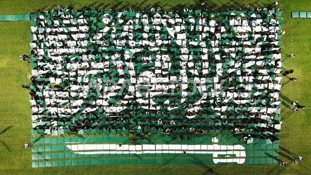 لقطة جوية التقطتها طائرة بدون طيار لعلم المملكة العربية السعودية الذي تشكل على شكل قطع فنية على أرض عشبية