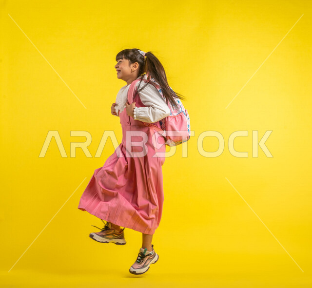 Portrait of a Saudi Arabian Gulf student, wearing a school uniform, carrying a school bag, gestures indicating happiness, walking and heading to school, preparing for the new school year, school stage, school education in Saudi Arabia, yellow background, 