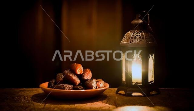 مفهوم رمضان. صورة مقربة للتمر في المقدمة. فانوس رمضاني على طاولة خشبية.