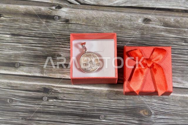 A red gift small decorated box with an Islamic pound coin of pure precious silver metal, 8 grams 999 features Kaaba and Masjid Al Haram mosque and the