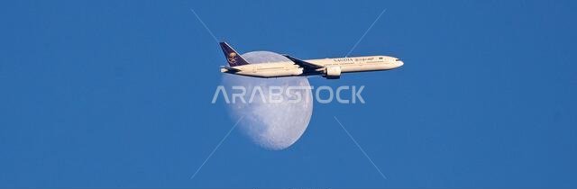 طائرة تابعة للخطوط الجوية السعودية من طراز إيرباص A350-900 تعبر القمر المتزايد فوق شمال لندن، المملكة المتحدة، أثناء اقترابها من مطار هيثرو.