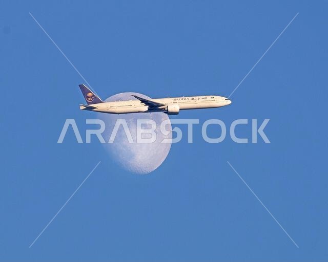 Saudi Arabian Airlines A350-900 plane passes the waxing moon above North London, United Kingdom as it approaches Heathrow Airport