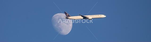 Saudi Arabian Airlines A350-900 plane passes the waxing moon above North London, United Kingdom as it approaches Heathrow Airport