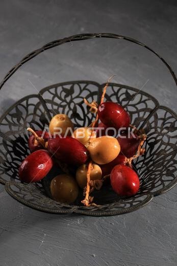 Red and Yellow Raw Dates Fruit or Kurma Muda (Ruthob) on Vintage Basket Above Rustic Background. COpy Space for Text