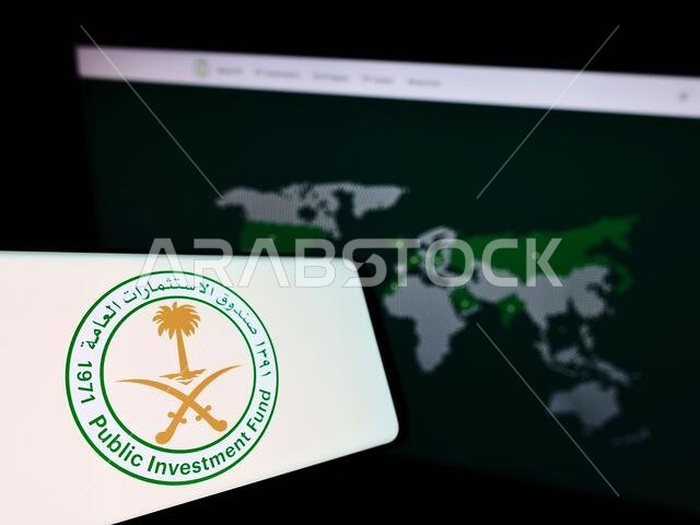 Cellphone with logo of Saudi Arabian Public Investment Fund (PIF) on screen in front of business website. Focus on center-left of phone display.