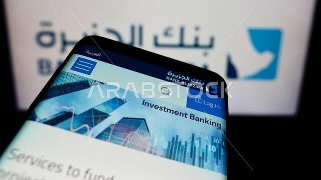 هاتف محمول يعرض صفحة ويب تابعة لشركة بنك الجزيرة (BAJ) السعودية أمام شعار الشركة. ركّز على الزاوية العلوية اليسرى من شاشة الهاتف.