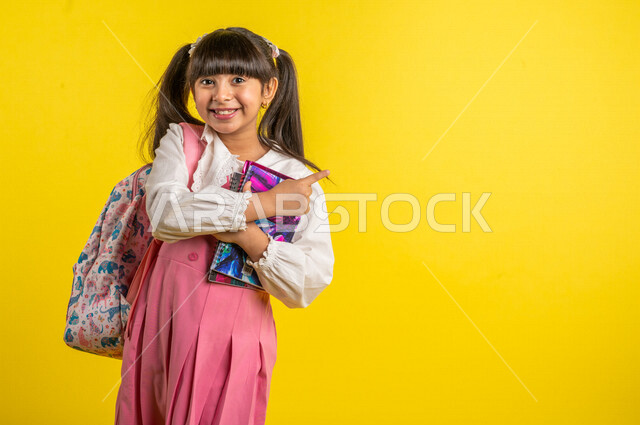 Portrait of a smiling Arab Gulf student, wearing a school uniform, carrying a school backpack, gestures indicating enthusiasm and happiness for the return of schools, preparing for the new school year, school education in Saudi Arabia, yellow background, 