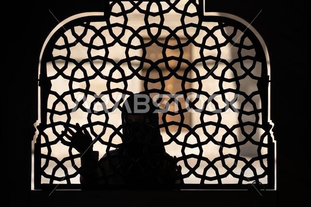 فتاة مسلمة ترتدي حجاباً أسود تقف خلف سياج من الحديد المطاوع المزخرف. فتاة مسلمة ترتدي حجاباً أسود تقف خلف سياج من الحديد المطاوع المزخرف.