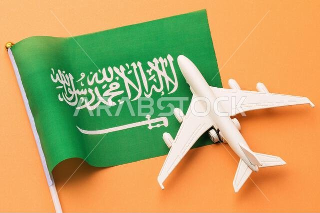 Saudi Arabia flag and toy plane on orange background, concept on the theme of travel to the country
