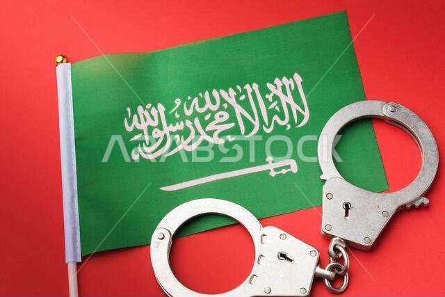 علم المملكة العربية السعودية وأصفاد على خلفية حمراء، مفهوم الجريمة في البلاد علم المملكة العربية السعودية وأصفاد على خلفية حمراء، مفهوم الجريمة في البلاد