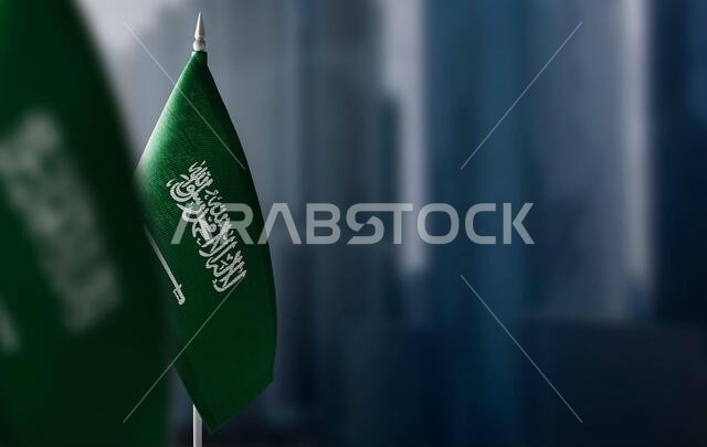 أعلام صغيرة للمملكة العربية السعودية على خلفية ضبابية للمدينة