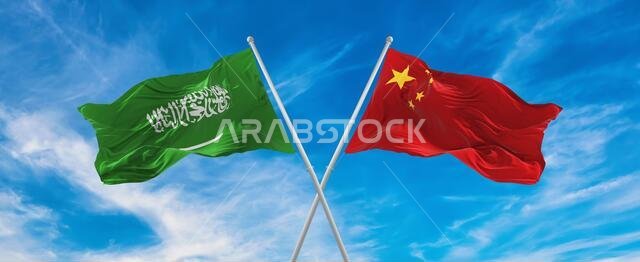flags of China and Saudi Arabia waving in the wind on flagpoles against sky with clouds on sunny day. Symbolizing relationship, dialog between two cou
