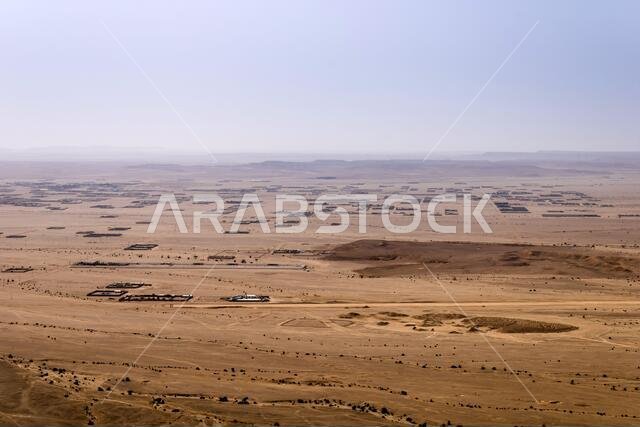 A desert landscape viewed from the Natural Arch of Riyadh. A plain surrounded by the mountain ridge - a Martian-like landscape.