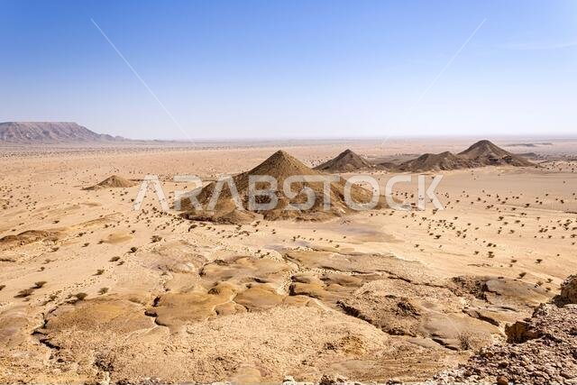 A desert landscape viewed from the Natural Arch of Riyadh. A plain surrounded by the mountain ridge - a Martian-like landscape.
