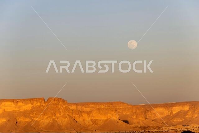 The Jabal Tuwaiq escarpment in Dhurma near Riyadh at sunset with full moon rising, Saudi Arabia