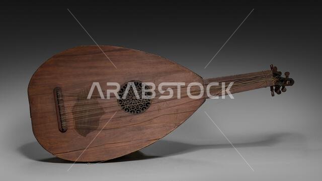 عود، أواخر القرن التاسع عشر - أوائل القرن العشرين. شمال المملكة العربية السعودية. خشب، أمعاء، ومعدن؛ الأبعاد: 81.3 × 33.7 سم (32 × 13 1/4 بوصة). ينتمي العود إلى عائلة العوديات، ولعله أكثر الآلات الموسيقية رمزية في العالم الإسلامي. فقد كان يُستخدم في الولائم والتجمعات، ويُصاحب الشعراء، ويُضفي رونقًا على الاحتفالات والمهرجانات، ولا يزال يحظى بمكانة بارزة حتى اليوم. وقد ذُكر العود في كتاب الموسيقى الكبير للفيلسوف الفارابي (872-950/951)، حيث وصفه فيه