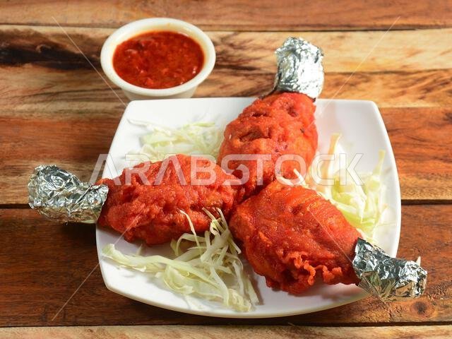 Tasty and spicy deep fried Chicken drumstick served on wooden background. Dishes and appetizers of indian cuisine, selective focus