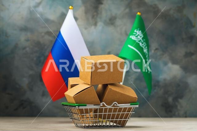 Various boxes in a food basket and two flags on an abstract background, the concept of trade between Saudi Arabia and Russia