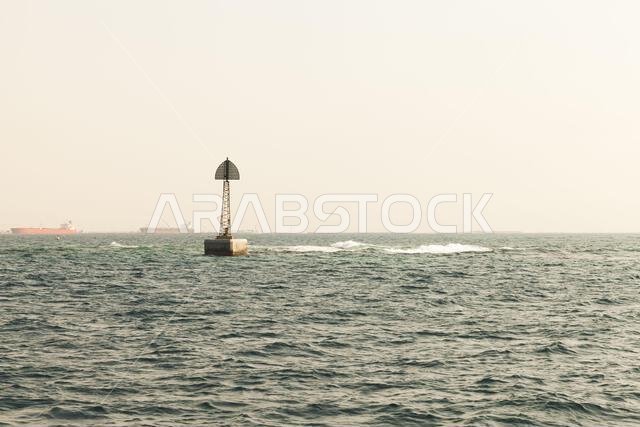 Beacon tower is on the border of a fairway, framed structure with triangle top mark stands in water of Persian Gulf, Saudi Arabia