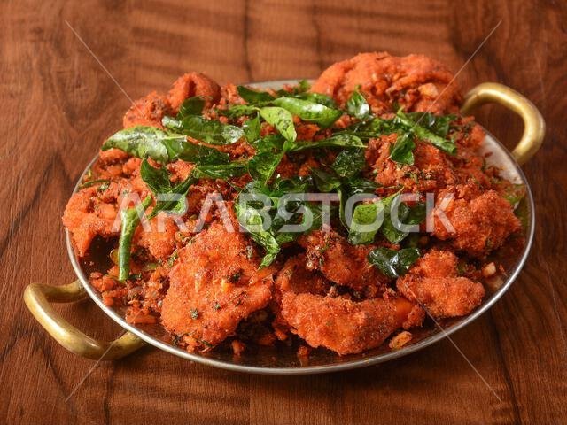 Tasty and Spicy Fried Chicken served on wooden background. Dishes and appetizers of indian cuisine, selective focus