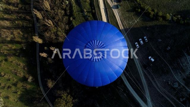 Aerial view of a blue balloon in the sky over the countryside area, France. Shot. Flying above trees, bushes, green fields, and park cars Aerial view of a blue balloon in the sky over the countryside area, France. Shot. Flying above trees, bushes, green fields, and park cars