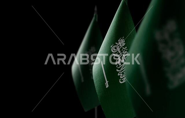 Small national flags of the Saudi Arabia on a black background