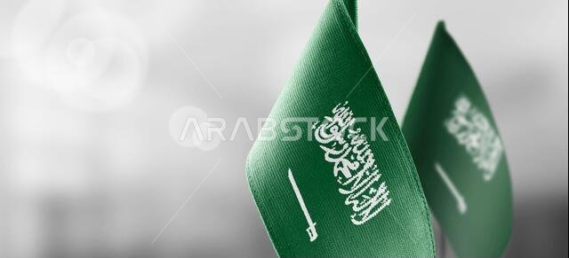 أعلام صغيرة للمملكة العربية السعودية على خلفية ضبابية فاتحة