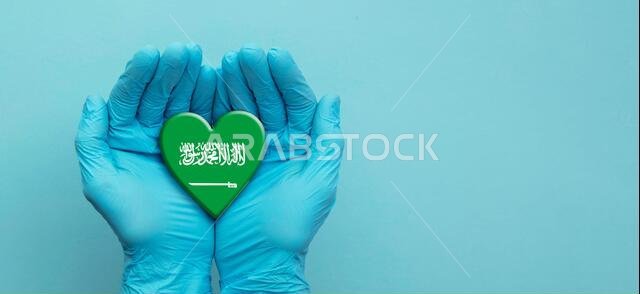 أيدي أطباء يرتدون قفازات جراحية تحمل علم المملكة العربية السعودية على شكل قلب