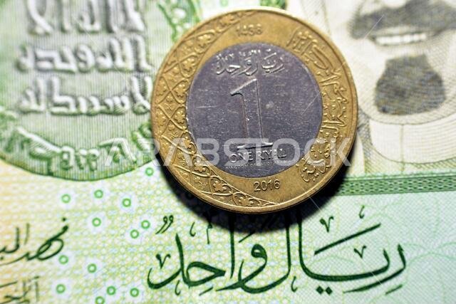 عملة معدنية من فئة ريال سعودي واحد (الوجه الخلفي) لعام 2016 على خلفية ورقة نقدية من فئة ريال سعودي واحد، ريال سعودي معدني وورقة نقدية معًا، سعودي