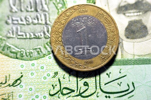 one Saudi Arabia riyal coin ( reverse side ) year 2016 on 1 Saudi riyal paper banknote background, one metal and banknote Saudi riyals together, Saudi