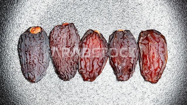 خمس حبات تمر مجففة كبيرة على خلفية سوداء وبيضاء