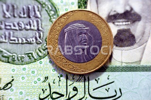عملة معدنية من فئة ريال سعودي واحد (الوجه الأمامي) لعام 2016 على خلفية ورقة نقدية من فئة ريال سعودي واحد، ريال سعودي معدني وورقة نقدية معًا، ريال سعودي واحد عملة معدنية من فئة ريال سعودي واحد (الوجه الأمامي) لعام 2016 على خلفية ورقة نقدية من فئة ريال سعودي واحد، ريال سعودي معدني وورقة نقدية معًا، ريال سعودي واحد