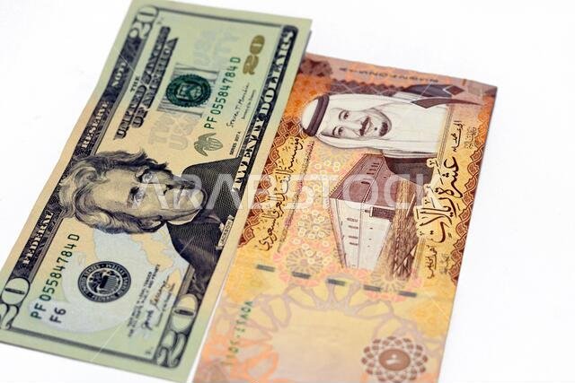 American 20 dollars with Saudi Arabia riyals currency banknotes of 10 Saudi Riyals with photo of king Salman, American money and Saudi Arabia riyals i