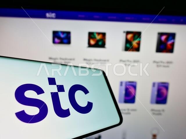 هاتف محمول يحمل شعار شركة الاتصالات السعودية (STC) أمام موقع الشركة الإلكتروني. التركيز على منتصف شاشة الهاتف.