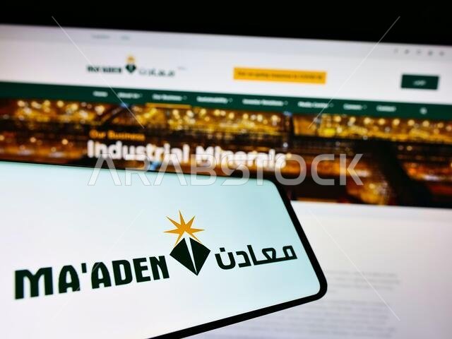 هاتف محمول يحمل شعار شركة التعدين السعودية (معادن) على الشاشة أمام موقع الشركة الإلكتروني. التركيز على منتصف يمين شاشة الهاتف. هاتف محمول يحمل شعار شركة التعدين السعودية (معادن) على الشاشة أمام موقع الشركة الإلكتروني. التركيز على منتصف يمين شاشة الهاتف.