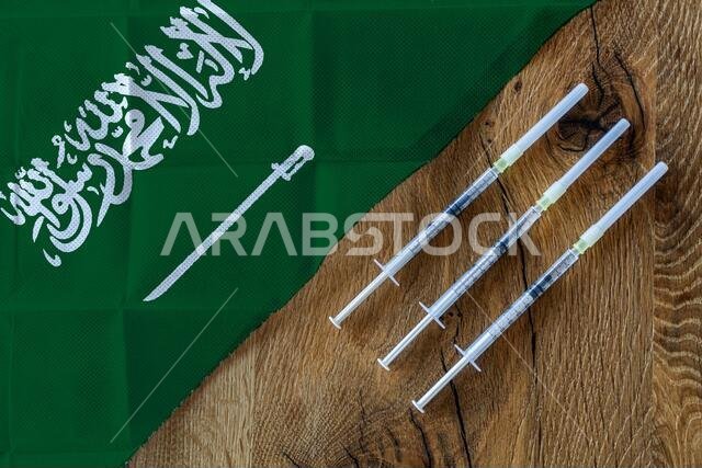 مفهوم الجهود المستمرة التي تبذلها المملكة العربية السعودية لتوفير وتوزيع لقاحات كوفيد-19، مع ثلاث محاقن على طاولة خشبية جاهزة للاستخدام مفهوم الجهود المستمرة التي تبذلها المملكة العربية السعودية لتوفير وتوزيع لقاحات كوفيد-19، مع ثلاث محاقن على طاولة خشبية جاهزة للاستخدام