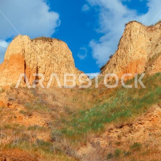 منظر طبيعي لجرف رأس الطين. عشب أخضر، ومروج تنمو على سفوح جبال الطين مقابل السماء الزرقاء. تلال جبلية وسفوح رأس الطين