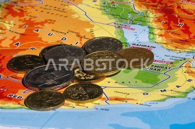 Money, coins of Ringgit Malaysia, Singapore dollar and Saudi Arabia Riyals on the map of Saudi Arabia, selected focus. Business, Finance, Economy and