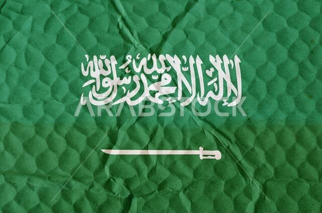 علم المملكة العربية السعودية الأخضر على سطح غير مستوٍ. العلم الوطني للدولة الواقعة في شبه الجزيرة العربية. يرمز إلى مفهوم الحرية والاستقلال.