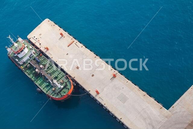 Tanker ship with green deck is moored in Jedda port on a sunny day, Saudi Arabia. Aerial view